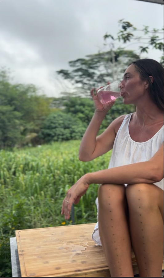 Woman drinking electrolytes in nature in a glass jar